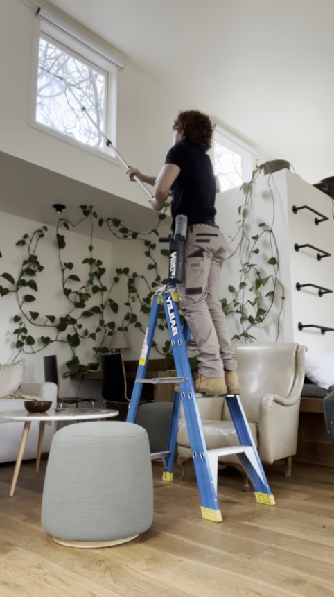 Justin cleaning interior windows in a Melbourne home